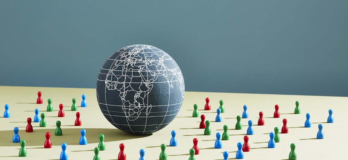 A world globe surrounded by people figurines