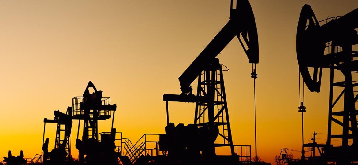 The silhouette of two oil pumps on a beautiful yellow sunset sky. Oil production well in Siberia